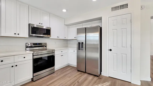 a kitchen with stainless steel appliances granite countertop a refrigerator stove and white cabinets