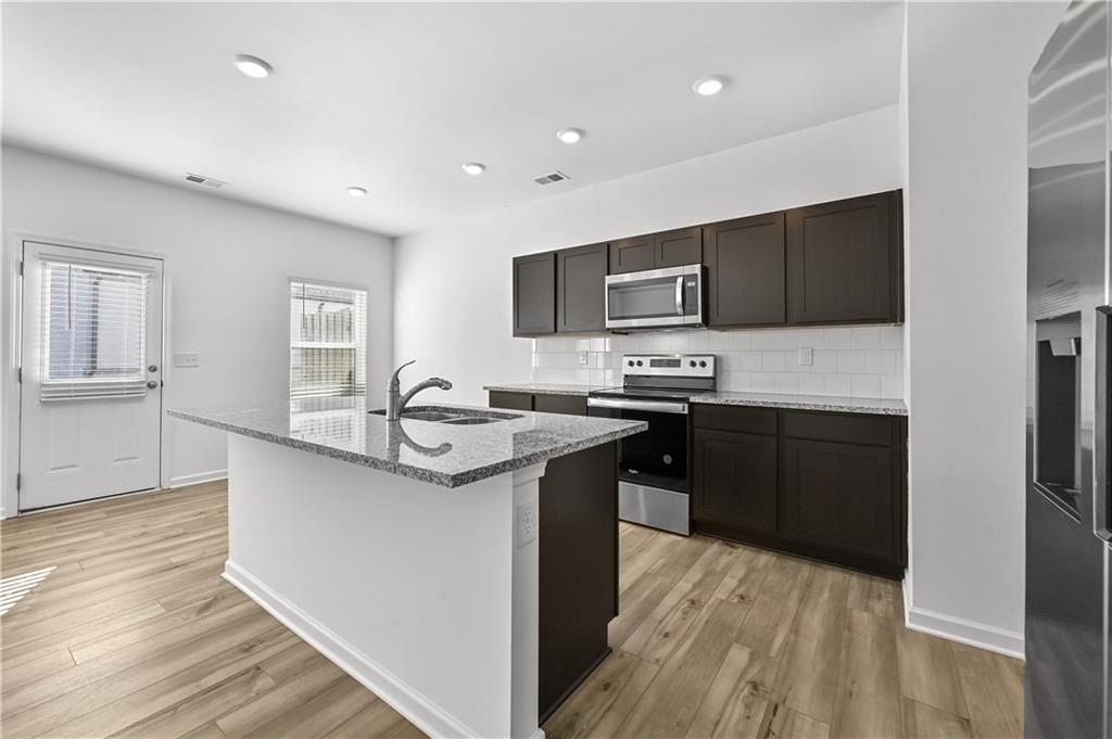 1102 Lossie Lane Grayson, GA 30017 - Photo 14 of 34 a kitchen with stainless steel appliances granite countertop a sink stove refrigerator and cabinets