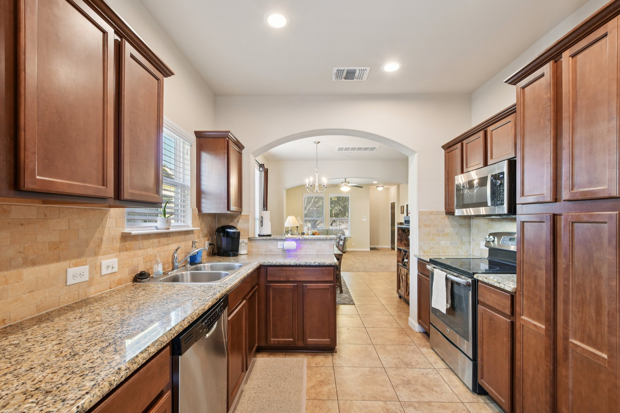 616 Lookout Tree Lane Round Rock, TX 78664 - Photo 9 of 39 Kitchen with stainless steel appliances, light stone counters, tasteful backsplash, and a peninsula