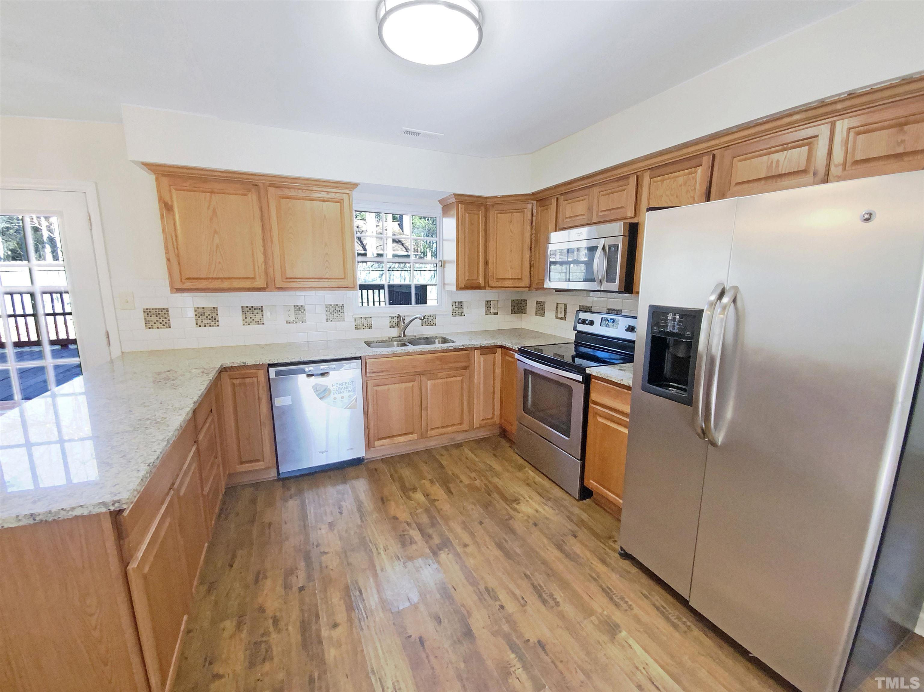 2508 Torbay Court Raleigh, NC 27613 - Photo 6 of 18 a kitchen with stainless steel appliances granite countertop wooden cabinets a refrigerator a sink a stove a microwave a counter space and cabinets