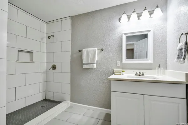 a bathroom with a sink shower and a mirror