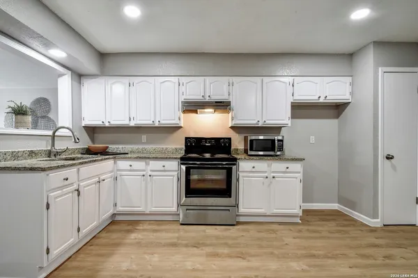 a kitchen with granite countertop white cabinets and appliances
