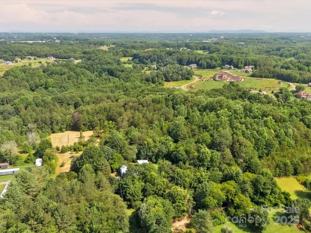 an aerial view of residential houses with outdoor space and trees