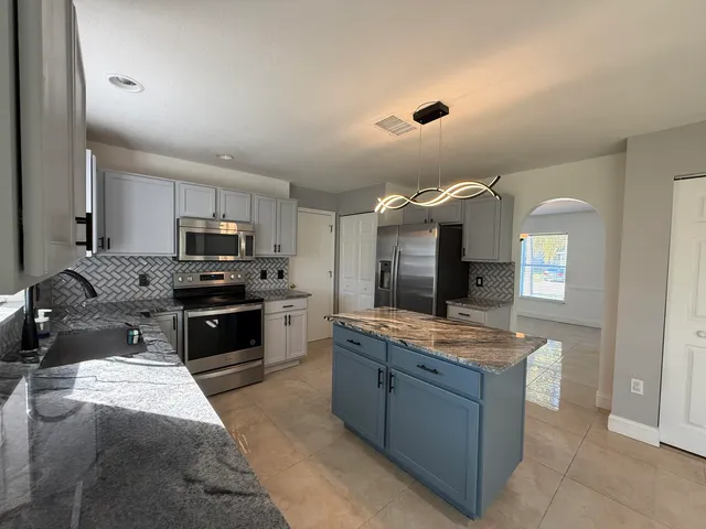 a large kitchen with granite countertop a large counter top and stainless steel appliances
