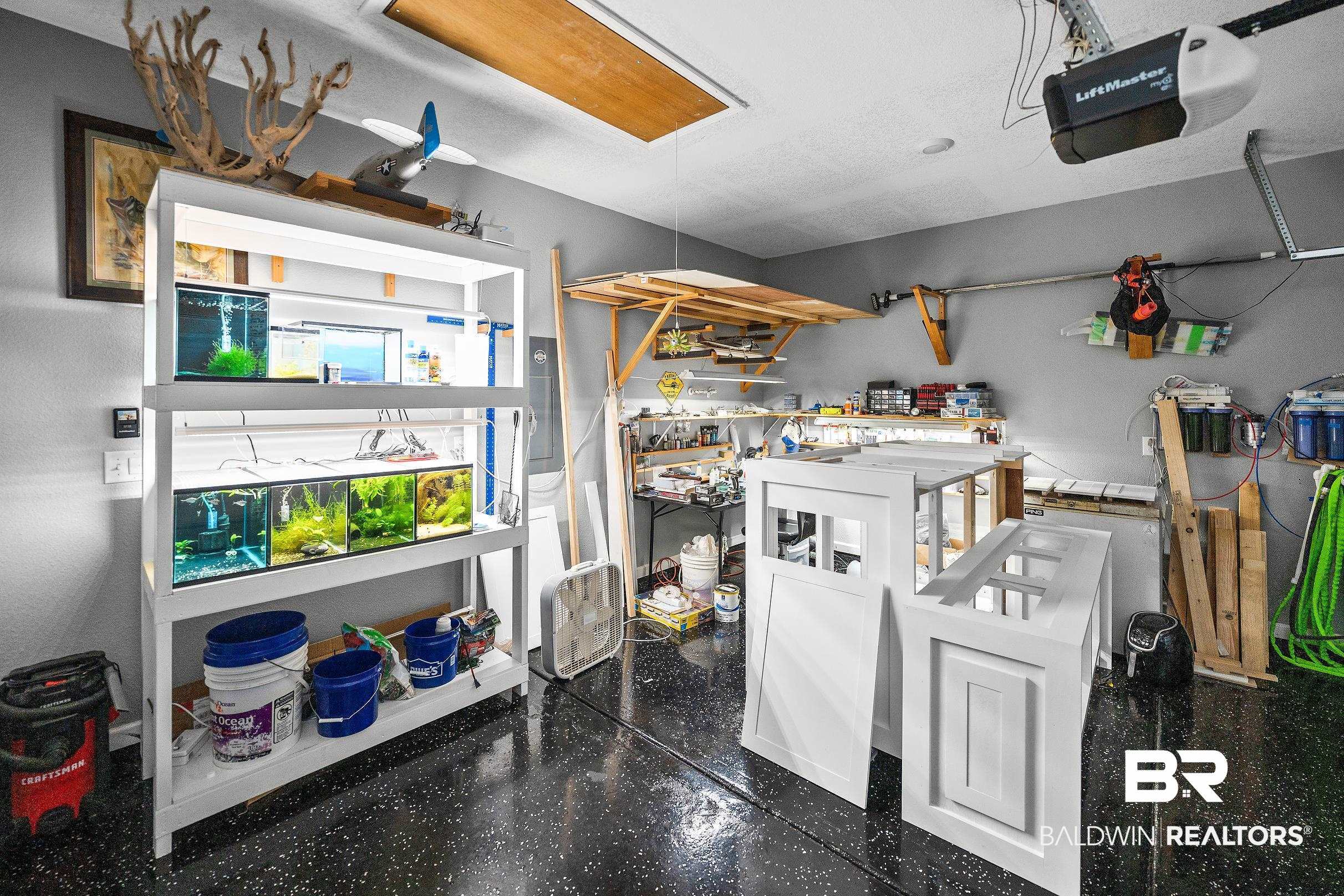 23997 Veranda Circle Elberta, AL 36530 - Photo 21 of 28 Spacious garage featuring a durable, speckled epoxy floor, overhead door opener, recessed lighting, and wall-mounted shelving