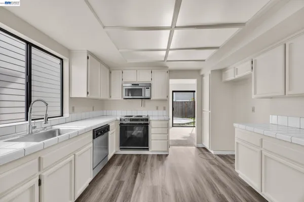 a kitchen with stainless steel appliances granite countertop hardwood floor sink stove and refrigerator