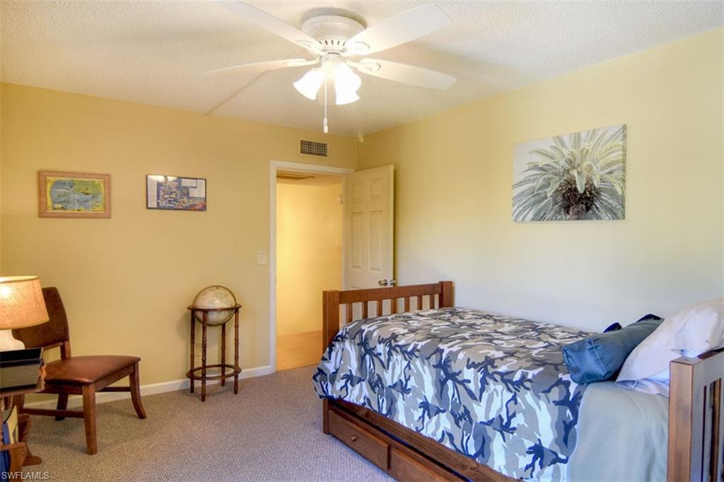 1468 Park Shore Circle, Unit 4 Fort Myers, FL 33901 - Photo 29 of 32 a bedroom with a bed a chandelier and a chair