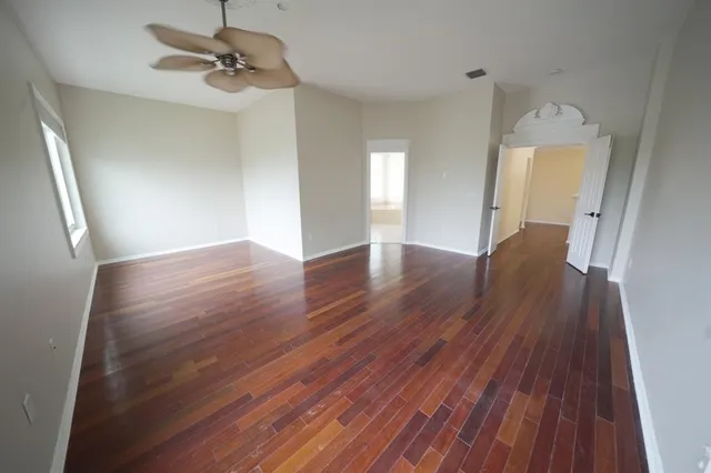 an empty room with wooden floor and windows