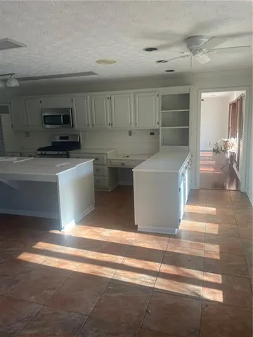 a living room with stainless steel appliances kitchen island granite countertop a refrigerator and a stove