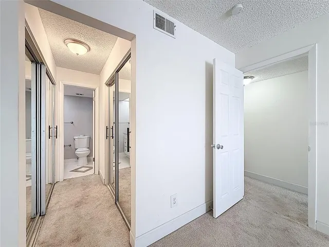 a view of a hallway with wooden floor and a bathroom