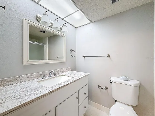 a bathroom with a granite countertop sink mirror vanity and toilet