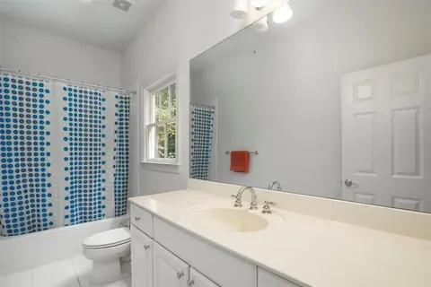 a bathroom with a granite countertop sink a toilet a mirror and shower curtain