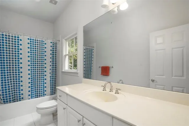 a bathroom with a granite countertop sink a toilet a mirror and shower curtain