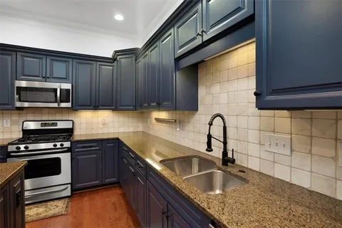 a kitchen with granite countertop a sink stainless steel appliances and cabinets