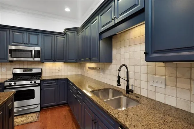 a kitchen with granite countertop a sink stainless steel appliances and cabinets