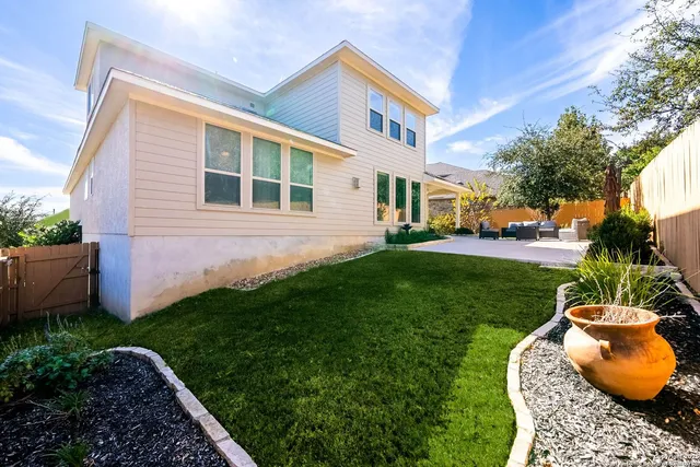 a backyard of a house with table and chairs plants and large trees