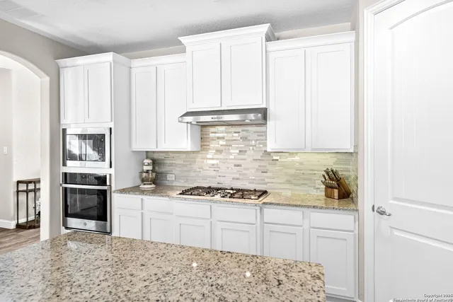 a kitchen with granite countertop a stove sink and cabinets