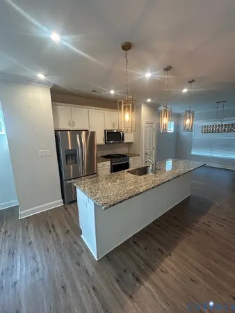 a large kitchen with granite countertop a large counter top and wooden floors