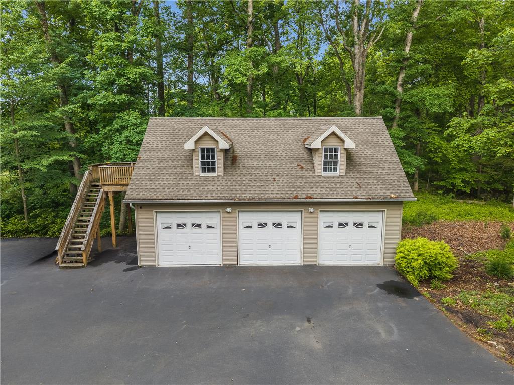 465 Raubsville Road Easton, PA 18042 - Photo 5 of 60 Three garage bays with a separate staircase access to the upper level amidst a wooded backdrop.