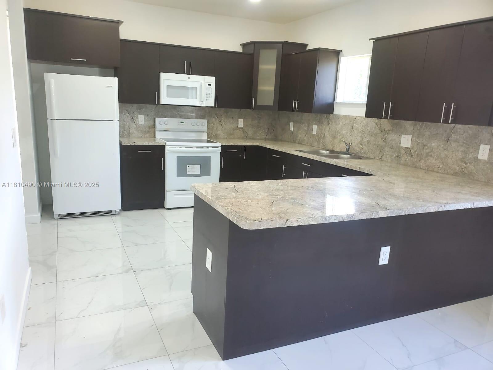 Brownsville Miami, FL 33142 - Photo 11 of 15 a kitchen with stainless steel appliances granite countertop a sink a stove a refrigerator a washer and dryer