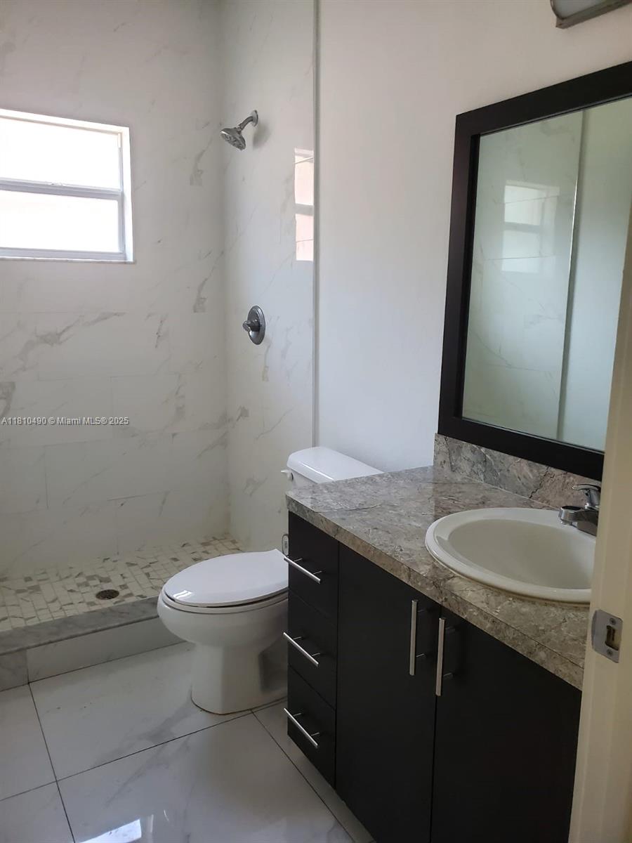 Brownsville Miami, FL 33142 - Photo 13 of 15 a bathroom with a granite countertop toilet a sink and a mirror
