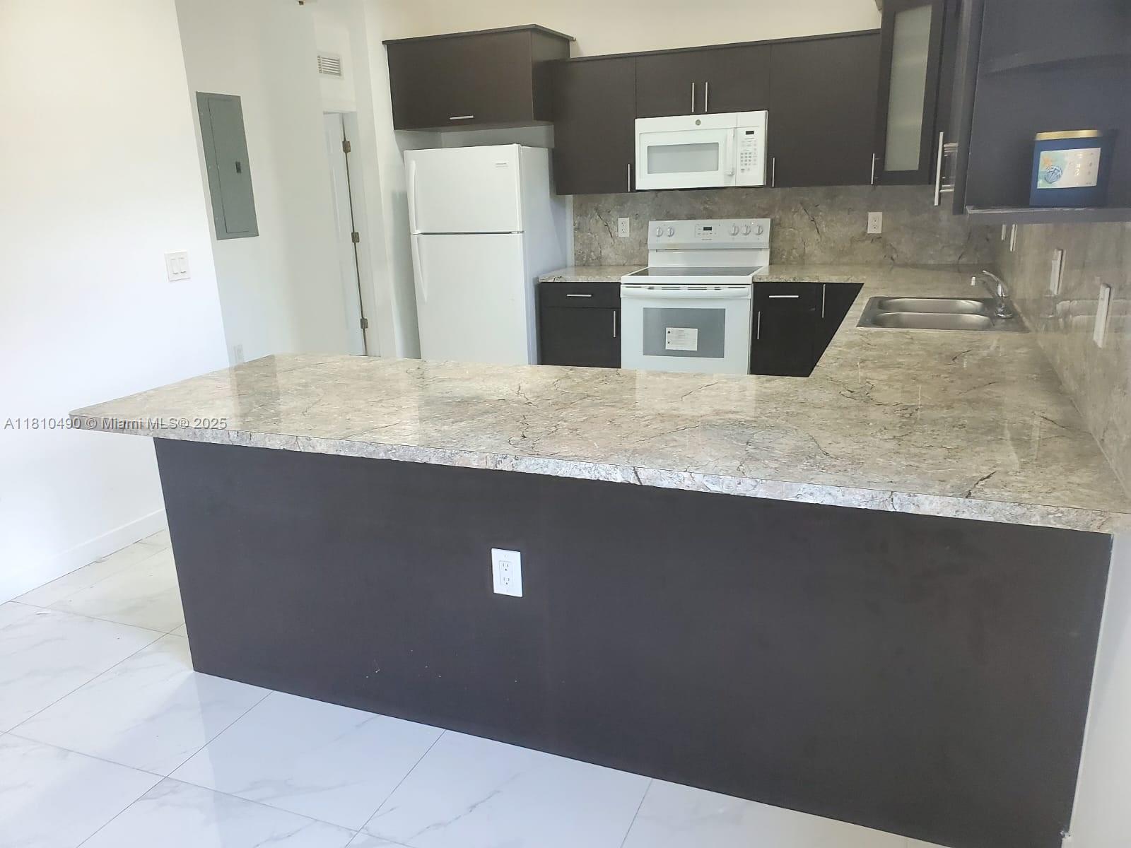 Brownsville Miami, FL 33142 - Photo 9 of 15 a kitchen with granite countertop a sink a stove and refrigerator