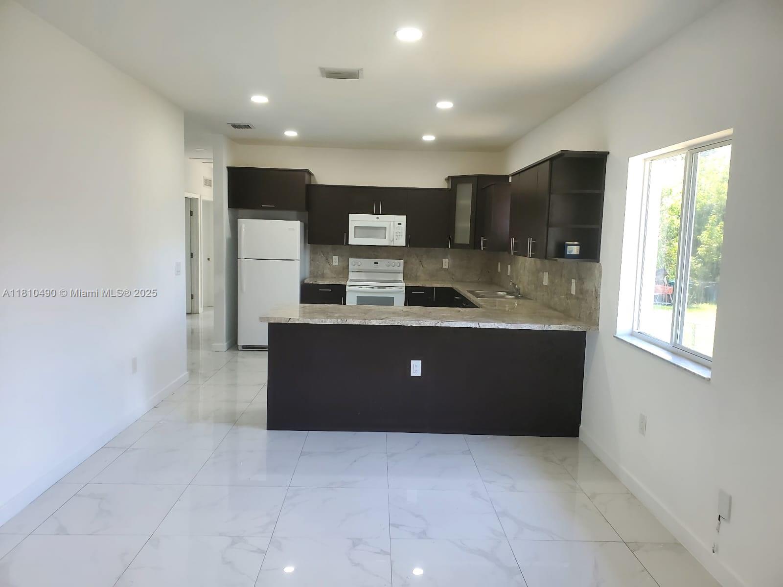 Brownsville Miami, FL 33142 - Photo 10 of 15 a large bathroom with a large mirror vanity and shower