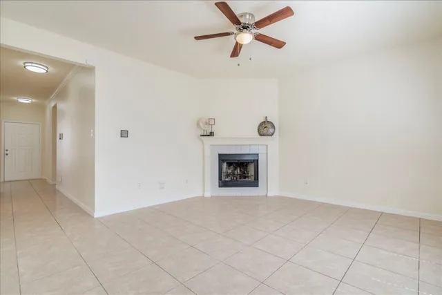 an empty room with a fireplace and a ceiling fan