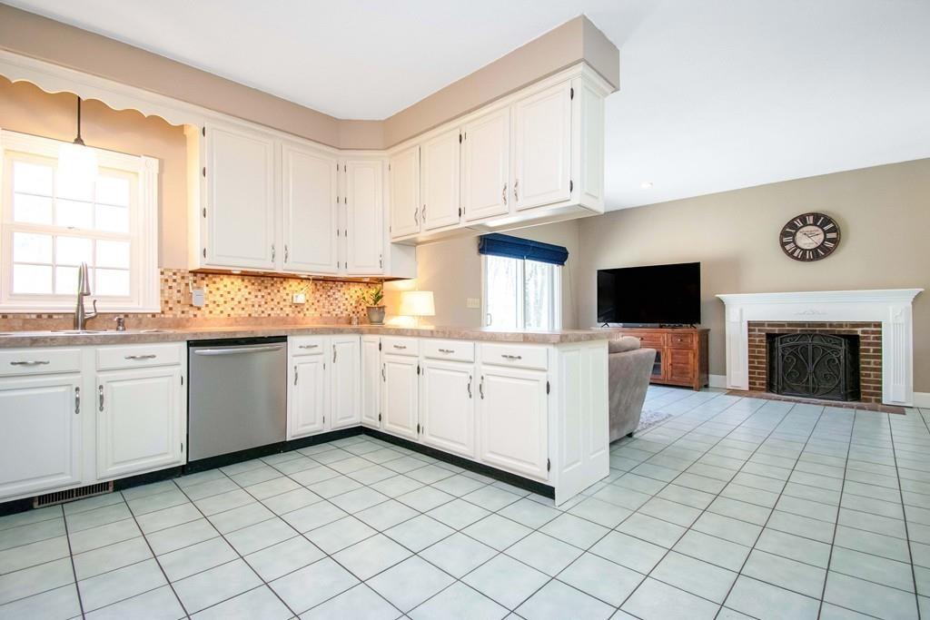51 Steele Road Enfield, CT 06082 - Photo 8 of 42 a kitchen with white cabinets a sink and a stove with wooden floor