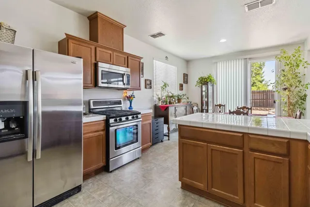 a kitchen with stainless steel appliances granite countertop a refrigerator a sink a stove a washer and a refrigerator