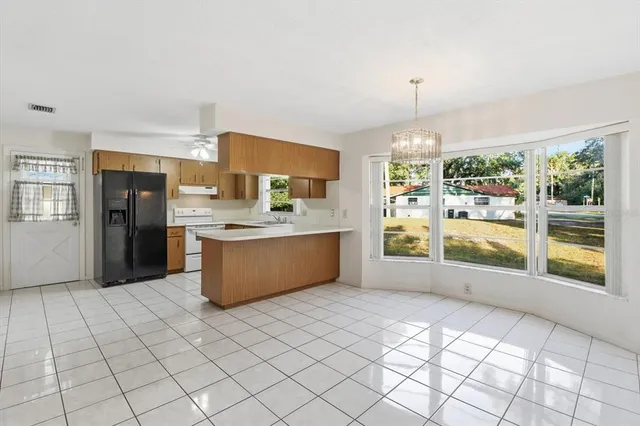 a large kitchen with a stove a refrigerator a sink dishwasher with a dining table and chairs