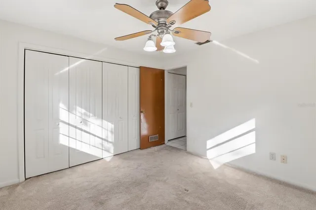 an empty room with windows and fan