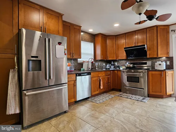 a kitchen with stainless steel appliances granite countertop a stove top oven a sink dishwasher a dining table and chairs with wooden floor