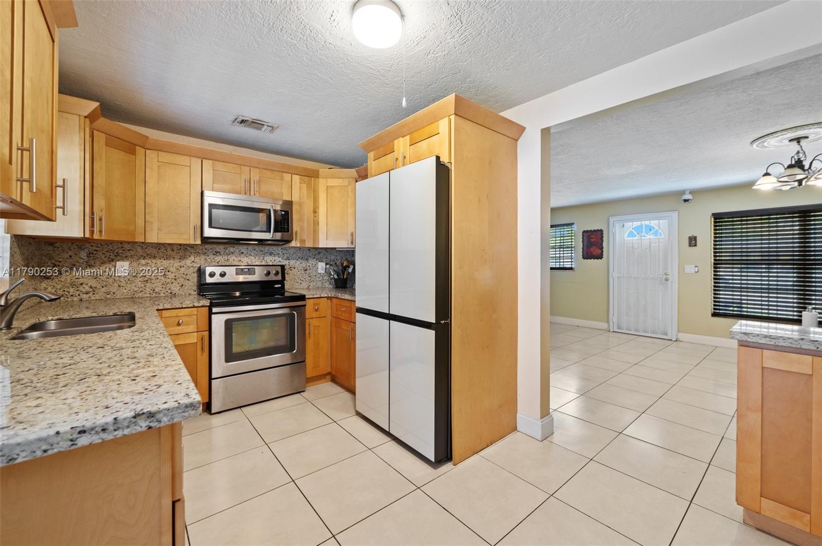 5731 Simms Street Hollywood, FL 33021 - Photo 13 of 33 a kitchen with stainless steel appliances granite countertop a refrigerator and a stove top oven