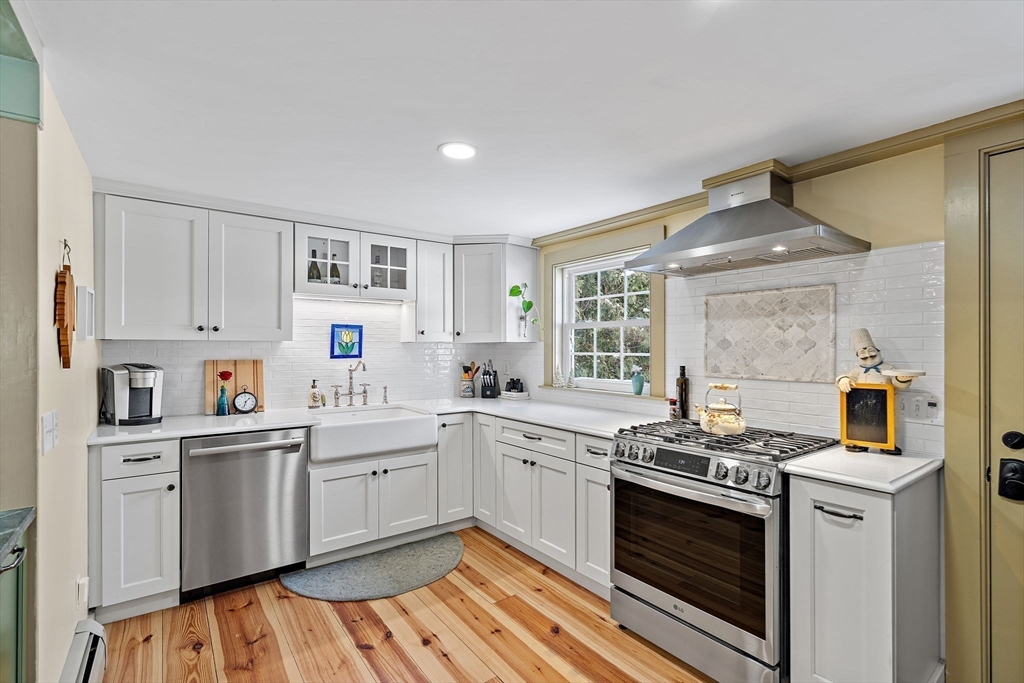 228 Main Street Groton, MA 01450 - Photo 17 of 33 a kitchen with stainless steel appliances a sink dishwasher stove and white cabinets with wooden floor