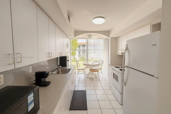 a kitchen with a sink a refrigerator and a stove top oven