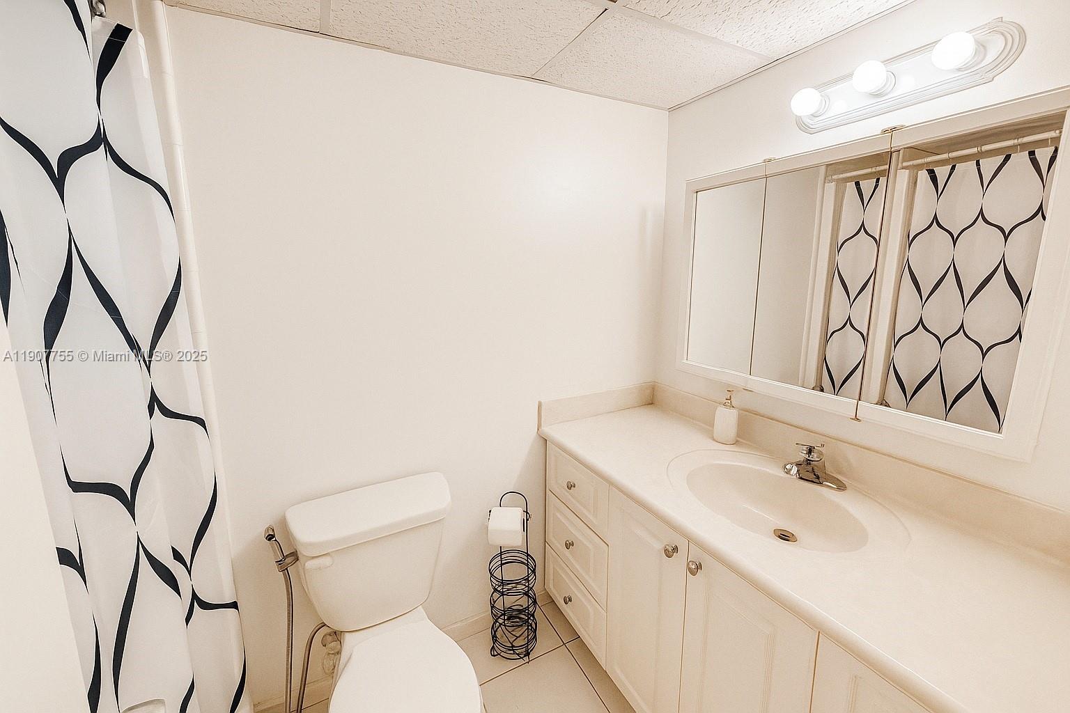 200 172nd Street, Unit 201 Sunny Isles Beach, FL 33160 - Photo 6 of 12 a bathroom with a toilet sink and mirror