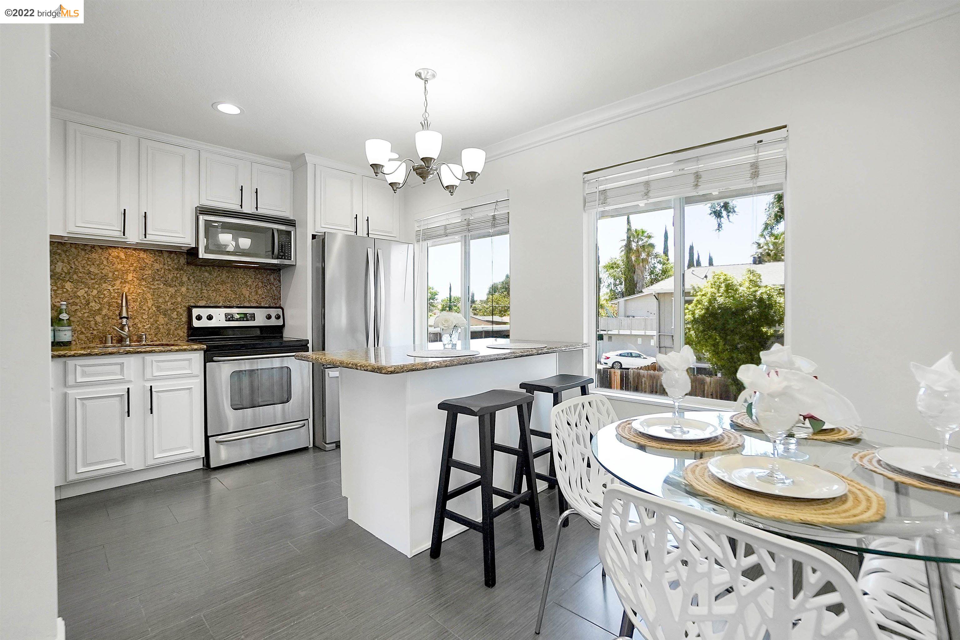4888 Clayton Road, Unit 44 Concord, CA 94521 - Photo 1 of 1 a kitchen with stainless steel appliances kitchen island granite countertop a sink a stove a microwave a dining table and chairs