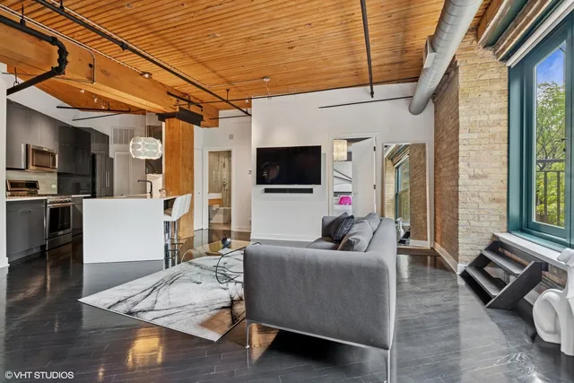 a living room with stainless steel appliances furniture and a kitchen view