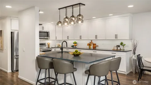 a kitchen with stainless steel appliances a dining table chairs refrigerator and microwave