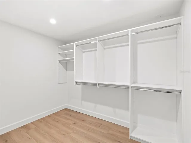 an empty room with wooden floor and ceiling fan