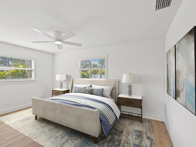 an empty room with wooden floor ceiling fan and windows
