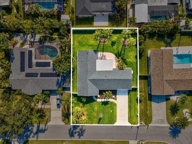 a backyard of a house with potted plants and palm trees