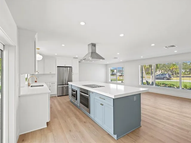 a kitchen with stainless steel appliances a kitchen island wooden floors and white cabinets