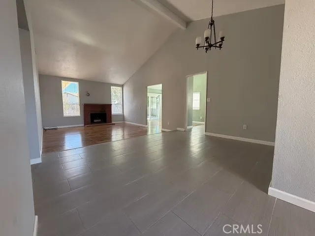 an empty room with wooden floor chandelier and glass door