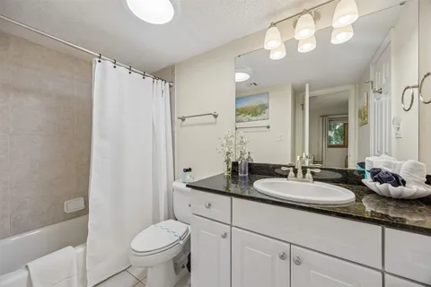 a bathroom with a granite countertop sink mirror vanity and toilet