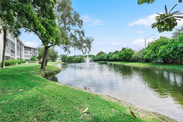 a view of a lake with a yard and large trees