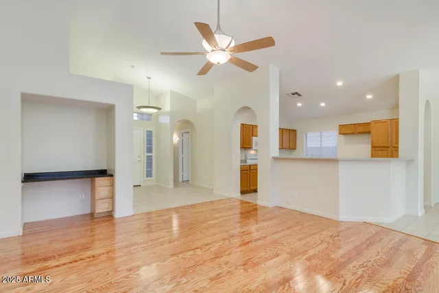 a view of a livingroom with a ceiling fan & kitchen space