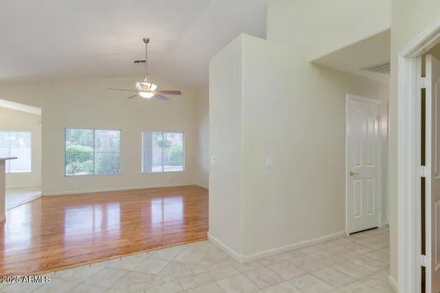 an empty room with windows and chandelier fan