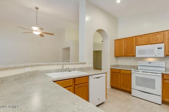 a kitchen with a sink dishwasher a stove and white cabinets with wooden floor